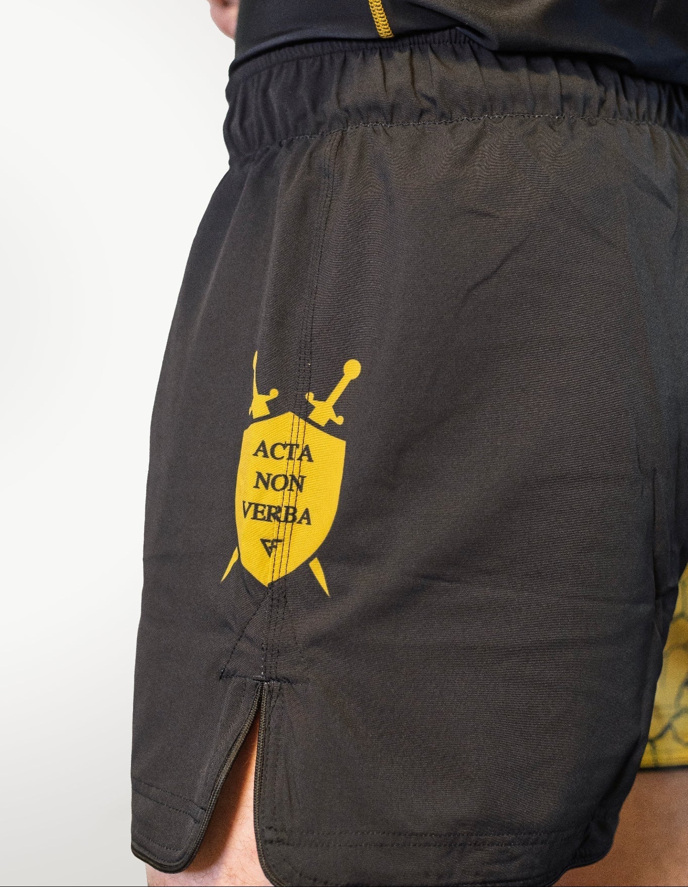 Black shorts with a yellow emblem on a white background