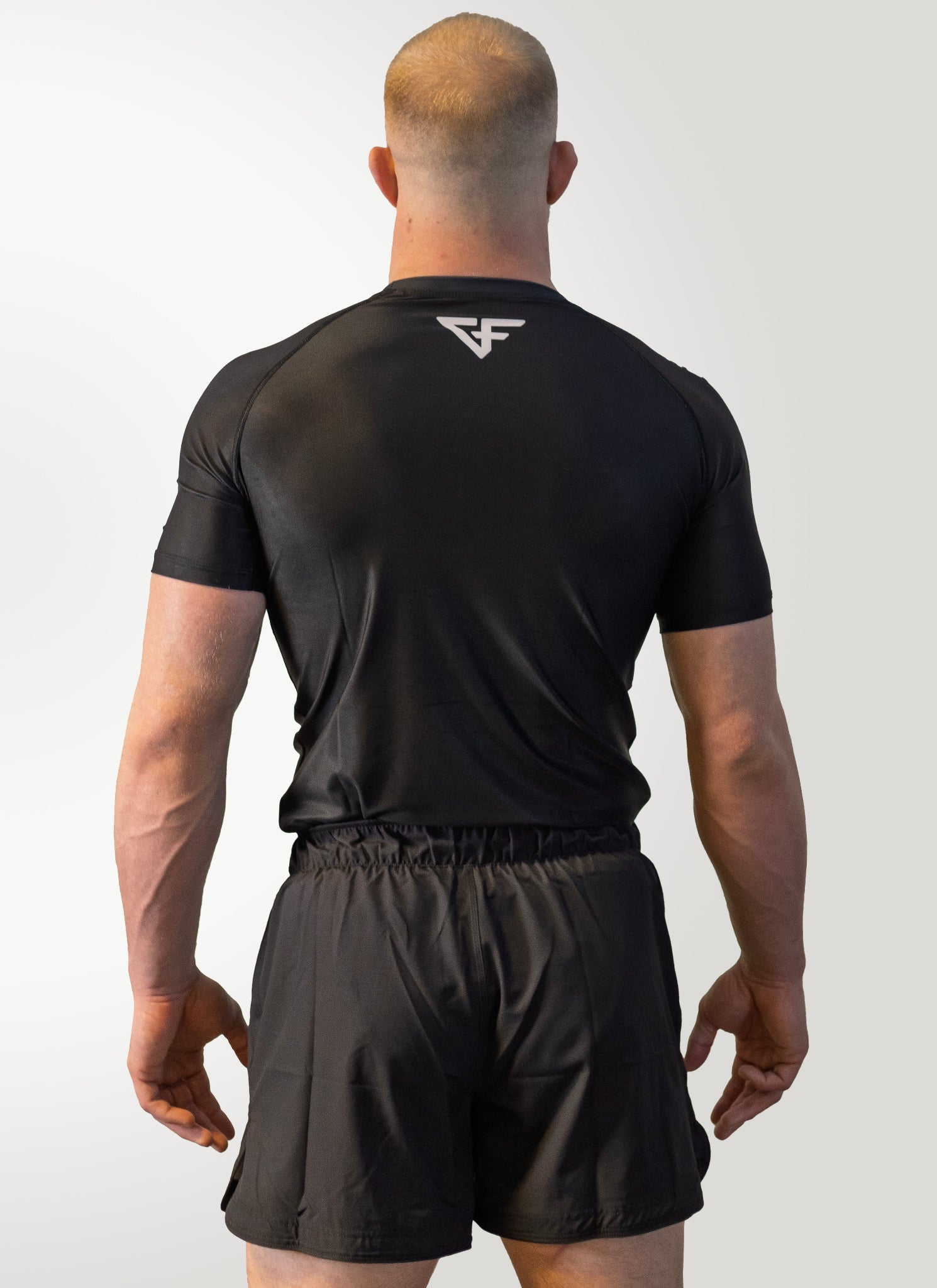 Person wearing a black athletic outfit with a logo on the back against a white background