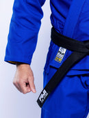 A person wearing the SEKAI 3.0 BJJ Gi Blue Yellow with a black belt labeled “FUJI JIU JITSU,” showing their fist and part of their torso.